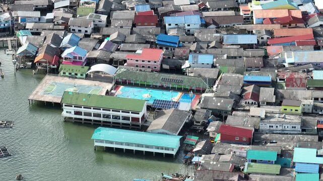 Aerial view of densely packed houses with vibrant roofs above the water, creating a colorful tapestry in Ko Panyi, Phang Nga, Thailand.