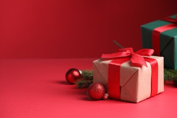 Gift boxes and Christmas decor on red background, closeup. Space for text