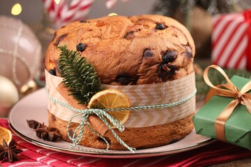 Tasty Christmas panettone cake with spices, fir branch and gift box on table against grey...