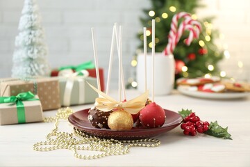 Sweet cake pops and Christmas decor on light wooden table against blurred lights