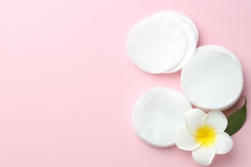 Clean cotton pads and plumeria flower on pink background, flat lay. Space for text