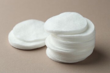 Stacks of clean cotton pads on beige background, closeup