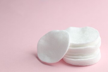 Stack of clean cotton pads on pink background, closeup. Space for text