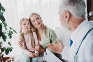 Obraz premium Caring doctor talks with mother and daughter during home health checkup fostering trust and family bonding in bright living room