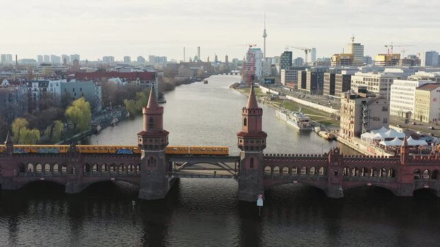 Aerial view of the iconic Oberbaum Bridge with a yellow train passing over it, reflecting off the Spree river, Berlin, Berlin, Germany.