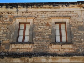 Due finestre di un palazzo antico in conci di pietra a Rosolini.