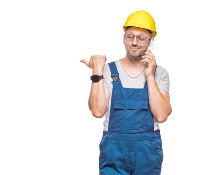 Pleased middle-aged construction worker talks on the smartphone, isolated on white background. Happy repairman using the smart phone. Craftsman against white wall