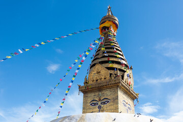 Prayer colorful buddhist flags fluttering in the wind on the Swayambhunath stupa in Kathmandu, Nepal.