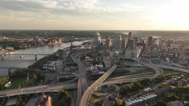 Aerial view of bridges spanning the river and the city skyline with skyscrapers, reflecting the golden hues of the setting sun, Cincinnati, Ohio, United States.