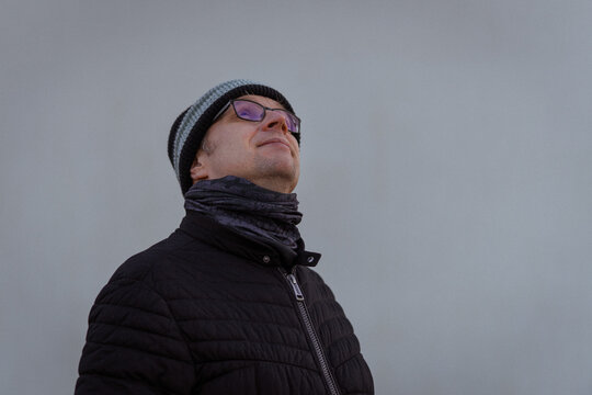 Man in Winter Clothing Looking Up Against Minimalist Light Background