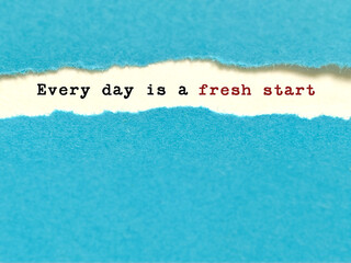 Positive daily motivation quote on torn paper with pastel blue background.