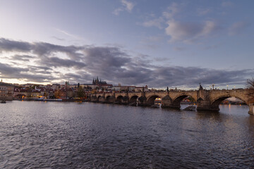Castle of Prague and Charles bridge reflected on Vltava river at sunset
