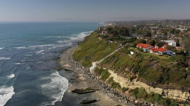 Aerial view of the Yogananda Ashram perched atop a cliff, the building's red roof contrasts the lush greenery and the meeting of land and sea, Encinitas, California, United States.