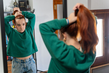 Young woman styling red hair getting ready for daily routine