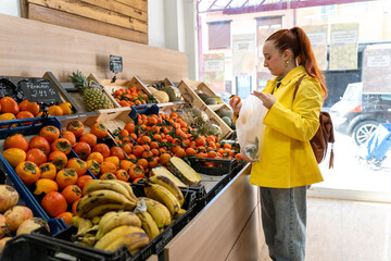 Young woman buying fresh fruit at local greengrocer’s
