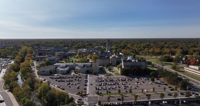 Aerial view of buildings with parking and roads surrounded by trees with changing seasonal colors and clear blue sky, Toledo, Ohio, United States.