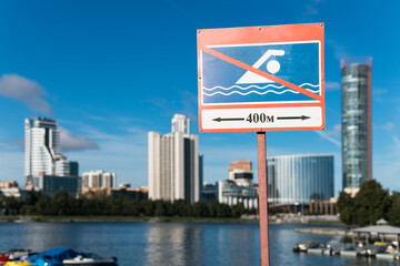 A sign on a pole in front of a body of water that says "No Swimming"