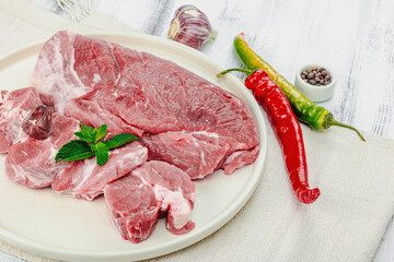 Raw pork meat. Traditional ingredients for cooking food. Garlic cloves, fresh basil and hot pepper