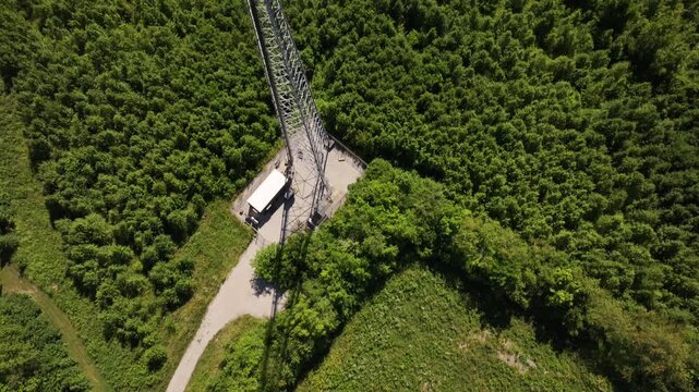 Aerial view of a tall cell tower standing prominently amid lush green trees, casting shadows, a contrast of technology and nature, Louisville, Kentucky, United States.
