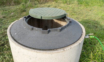 Concrete well ring with water hose.