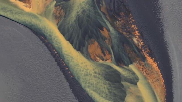 Aerial view of river delta displaying intricate patterns of sediment deposits in contrasting colors, creating a stunning natural artwork, Iceland.