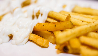 A plate of french fries with a white sauce on top