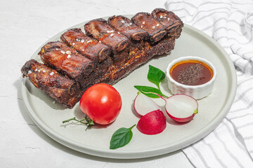 Baked pork ribs with spices, vegetables and sauce. Traditional ingredient for BBQ, picnic concept