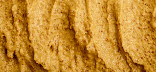Mustard sauce with grains close-up. Hot spices as a background. Texture of Dijon mustard.