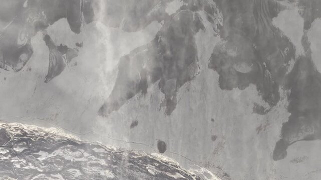 Aerial view of a stark, lunar-like landscape, the grey and white textures creating a mesmerizing pattern of nature, Skaftarhreppur, Iceland.