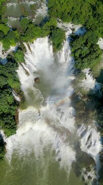 Aerial view of the majestic Detian Falls cascading down rugged cliffs amidst lush greenery, creating a mesmerizing spectacle, Chongzuo, Cao Bang, Vietnam.