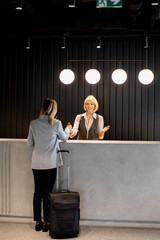 Friendly hotel receptionist welcoming a guest at the front desk during the day