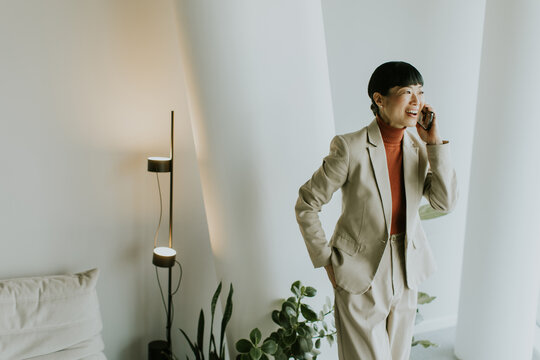 Professional woman in a beige suit smiling and talking on the phone in a modern room