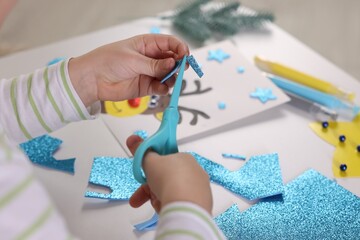 Little boy making Christmas postcard at table, closeup. Child handmade craft