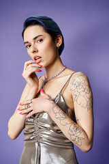 Obraz premium Stylish young woman with tattoos poses elegantly in vivid setting, showcasing contemporary fashion