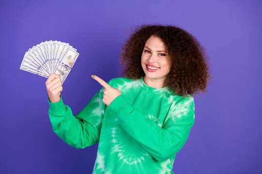 Young woman in green tie dye sweater holding cash and smiling as a stylish lifestyle advertising image for shopping and promotion