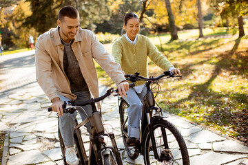 Obraz premium Couple enjoys a sunny autumn day biking together in the park