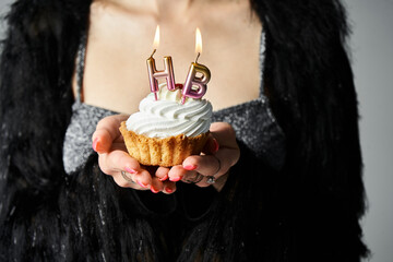 Celebrating a milestone with a stylish cupcake in hand and festive candles