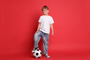 Cute boy with soccer ball on red background