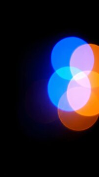 Cinematic extreme shallow depth of field shot focusing on large, brilliant blue and orange bokeh light orbs softly drifting and pulsing in the dark energy, softly drifting, maximal background