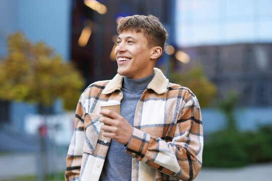 Smiling man in shirt with takeaway cup on city street