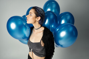 Young woman with stylish flair and blue balloons captures a moment of celebration