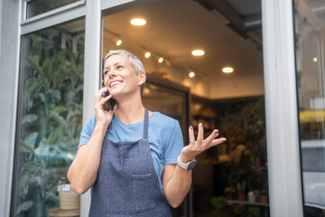 Portrait of female small business owner speaking by phone in flower shop, copy space