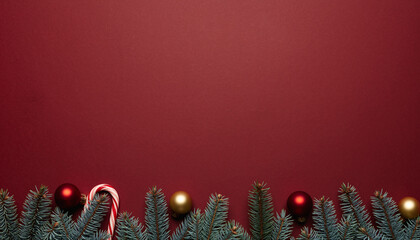 Christmas fir border with red gold baubles and candy cane on red background