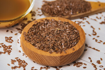 A pile of flax seeds and linseed oil on a wooden white table. Linen linen concept