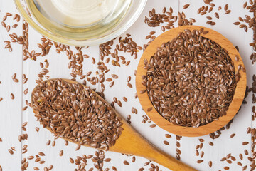 A pile of flax seeds and linseed oil on a wooden white table. Linen linen concept