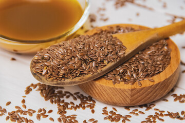 A pile of flax seeds and linseed oil on a wooden white table. Linen linen concept