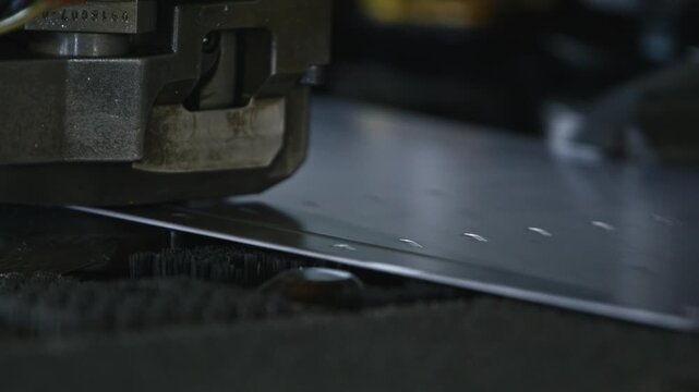 A machine punches precise holes into a metal sheet. Sparks and vibrations highlight the powerful industrial process in a workshop environment.