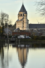 Le clocher de la collégiale Sainte-Gertrude se reflétant dans les eaux de l'étang du parc de la Dodaine en fin de journée d'automne à Nivelles (Brabant Wallon)