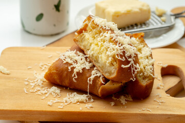 A sweet slice of Martabak Manis (Terang Bulan) topped with grated cheddar cheese and butter on a wooden board; a popular Indonesian street food snack