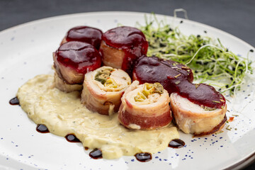 Chicken bacon roulade with berry sauce and creamy puree, plated with microgreens